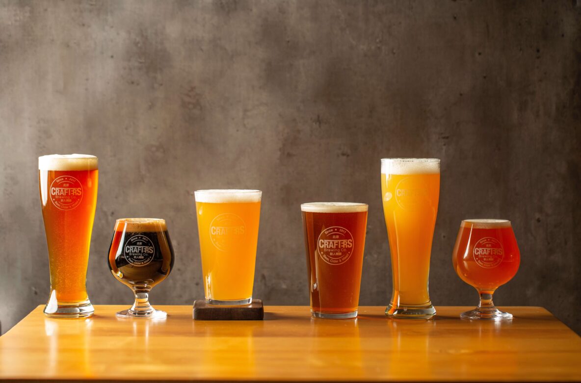 A variety of glasses of beer in a row.