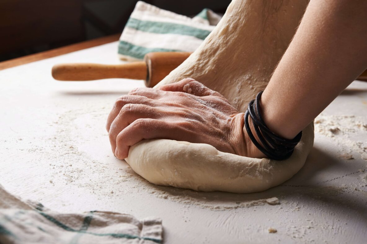 Pizza dough being needed by hand.
