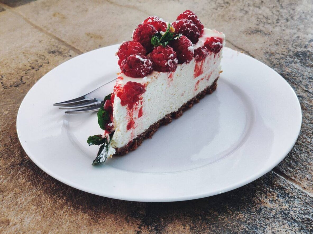 Cheesecake with raspberries in top on a plate.